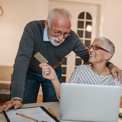 Mature man and woman using debit/credit card at laptop