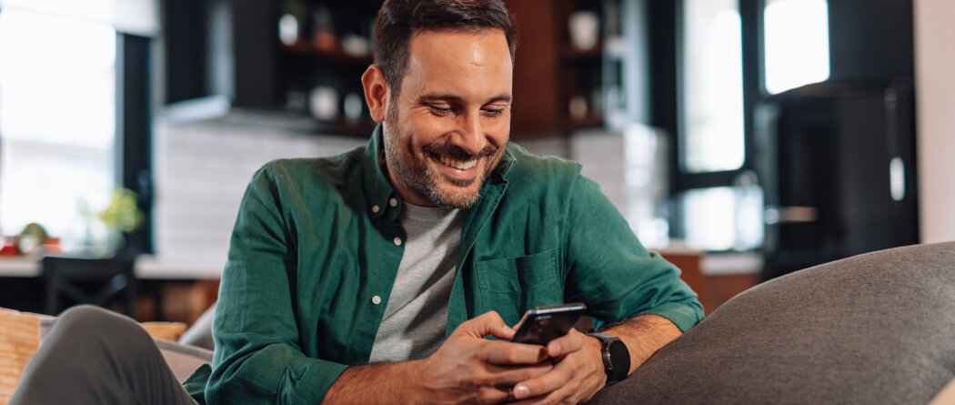Man sitting on a couch and using a smartphone