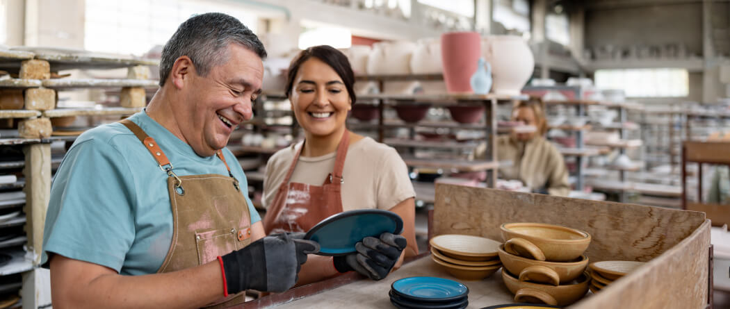 Two people in aprons in a pottery studio